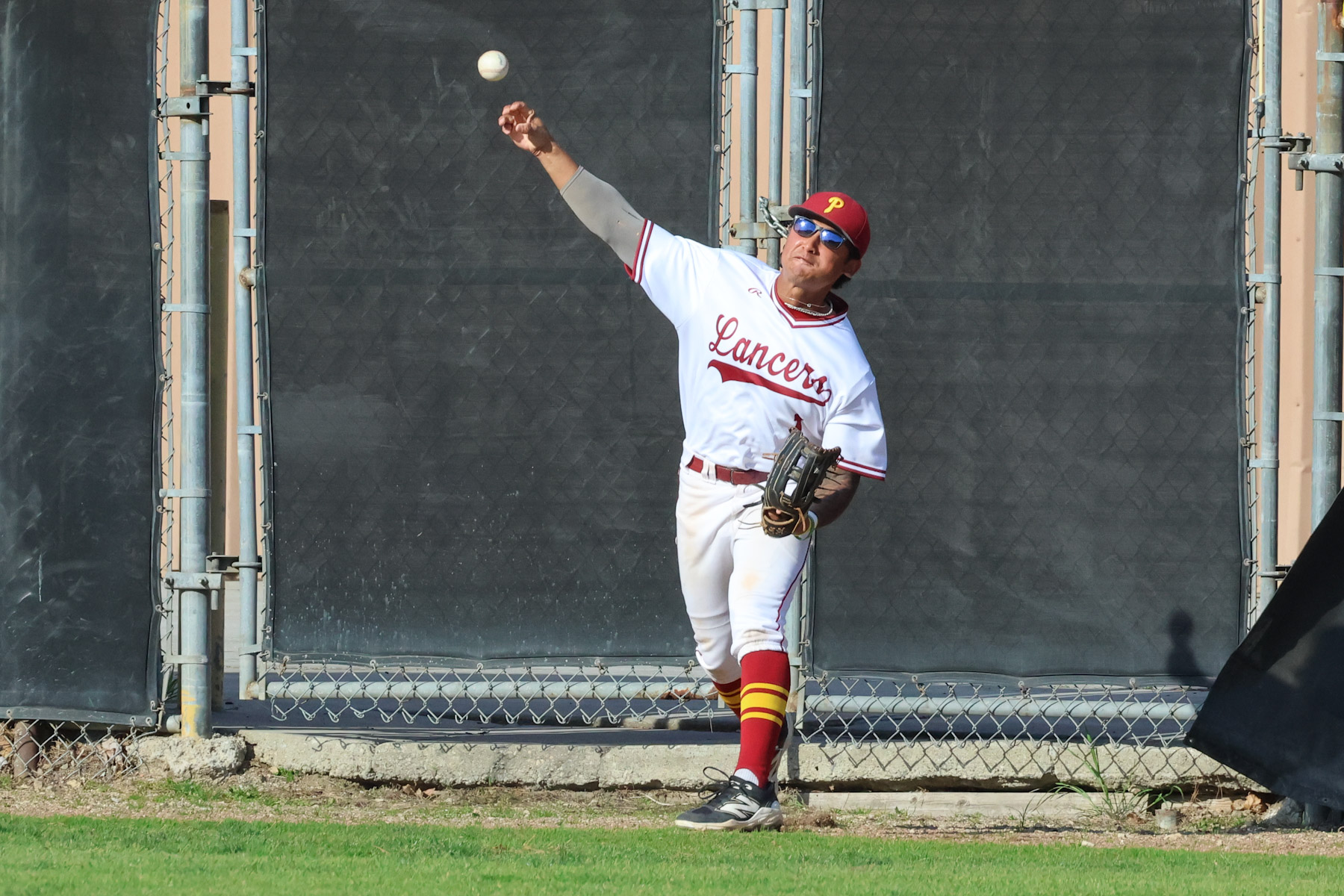 Issac Ton fires the ball after a catch near the fence during PCC's win on Wednesday (photo by Richard Quinton).