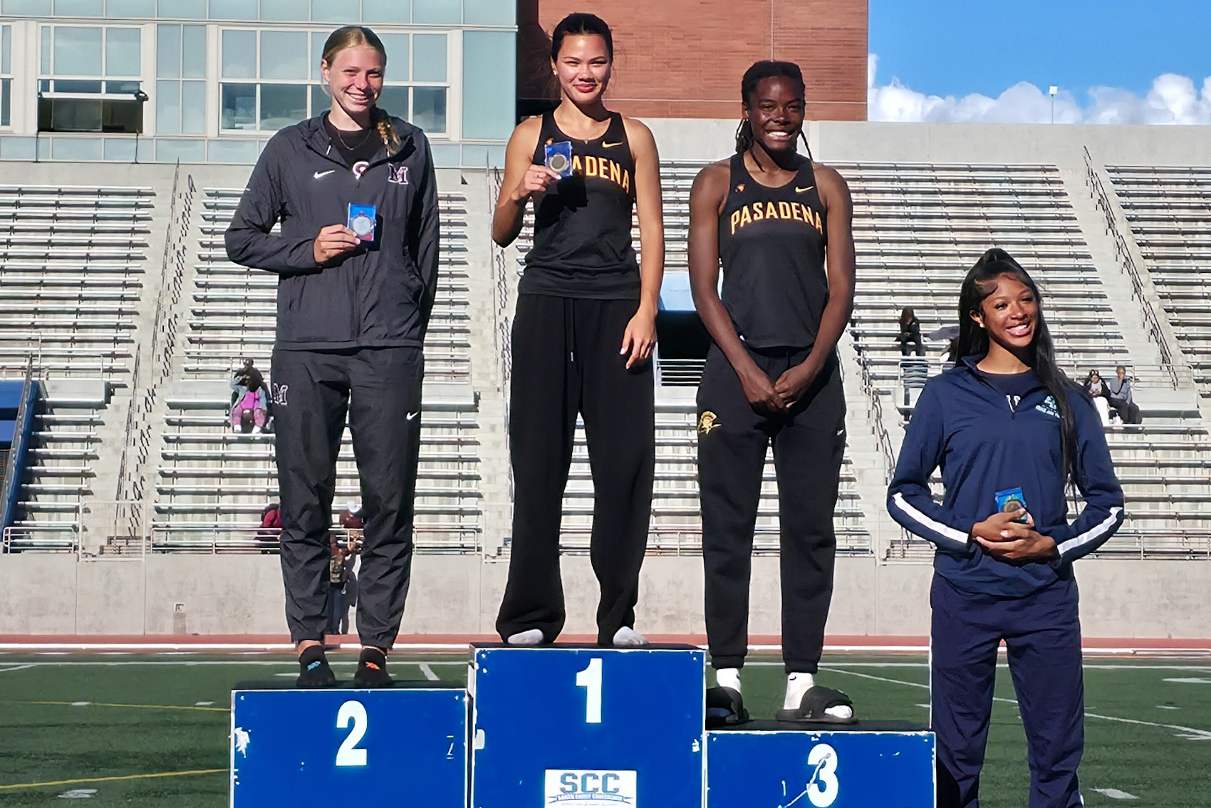 Kevia Gavlak shows off her first place medal after winning the SCC triple jump title (photo by Richard Quinton).